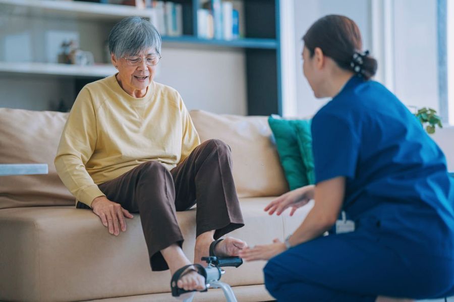 Physiotherapist helping an older adult with balance and strengthening at home